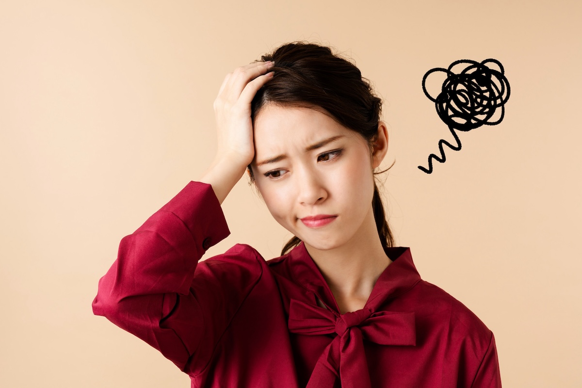 不満そうな顔で頭を抱える女性