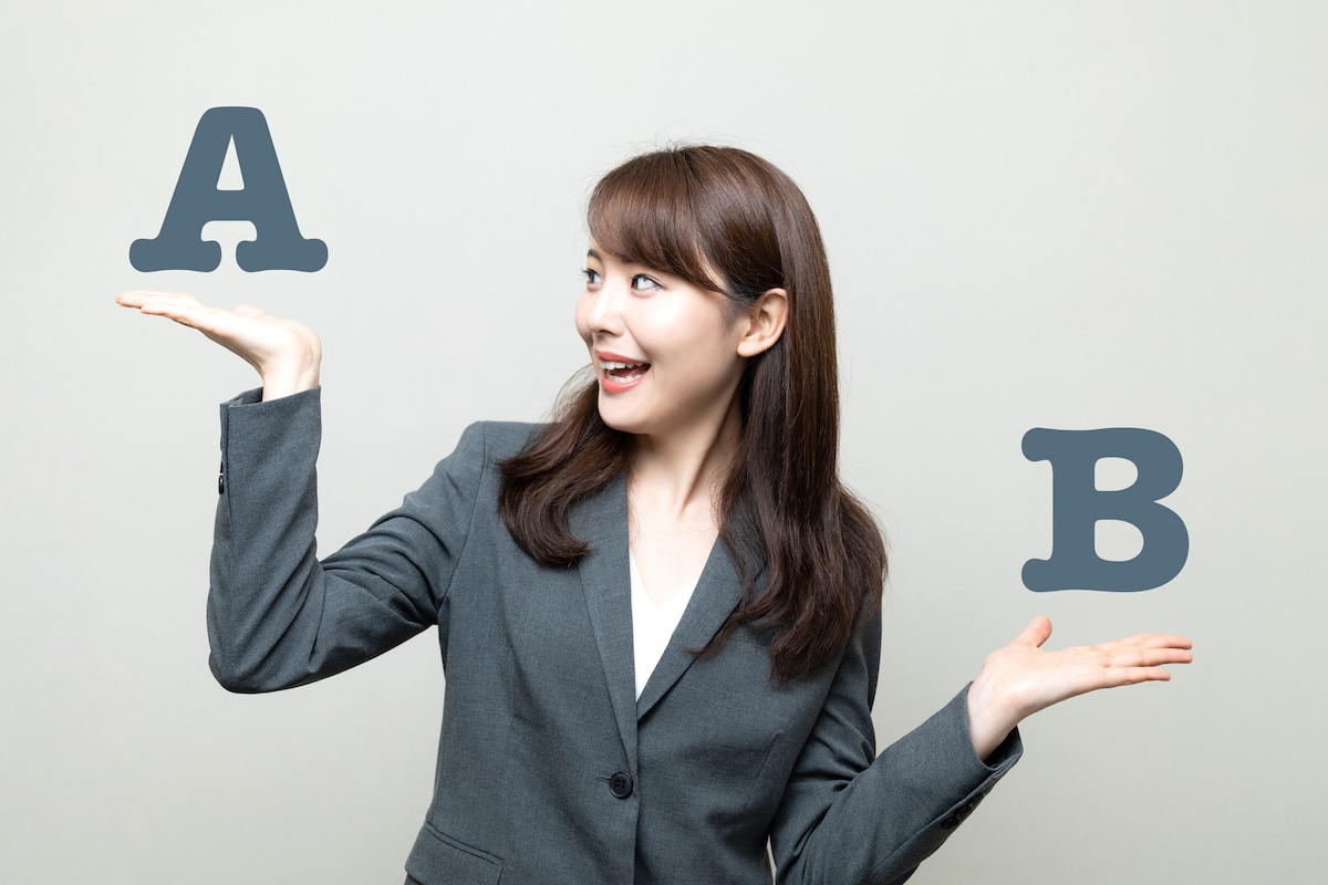 手のひらの上のAとBを比べるスーツ姿の女性